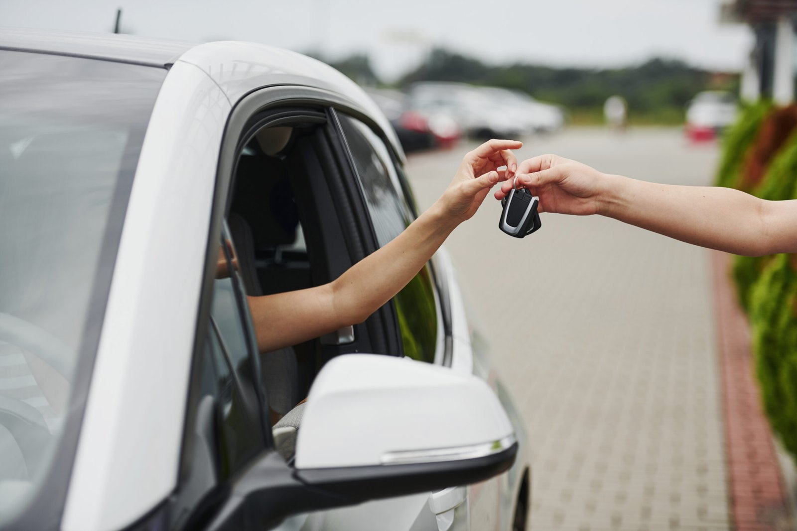 Taking keys of the car. Two people. Girl sitting in her brand new automobile.